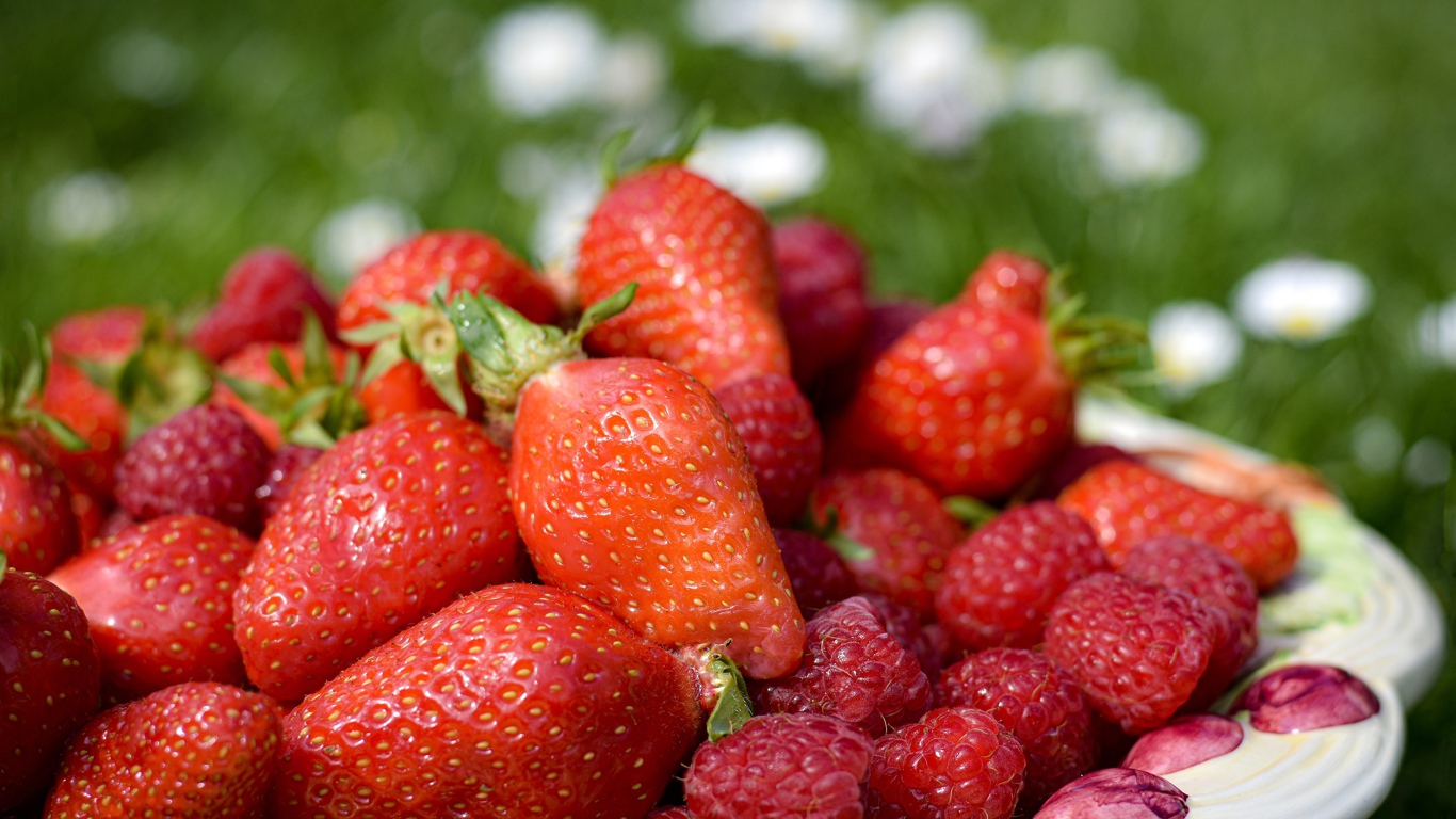 Спелая малина с ягодами клубники в тарелке 