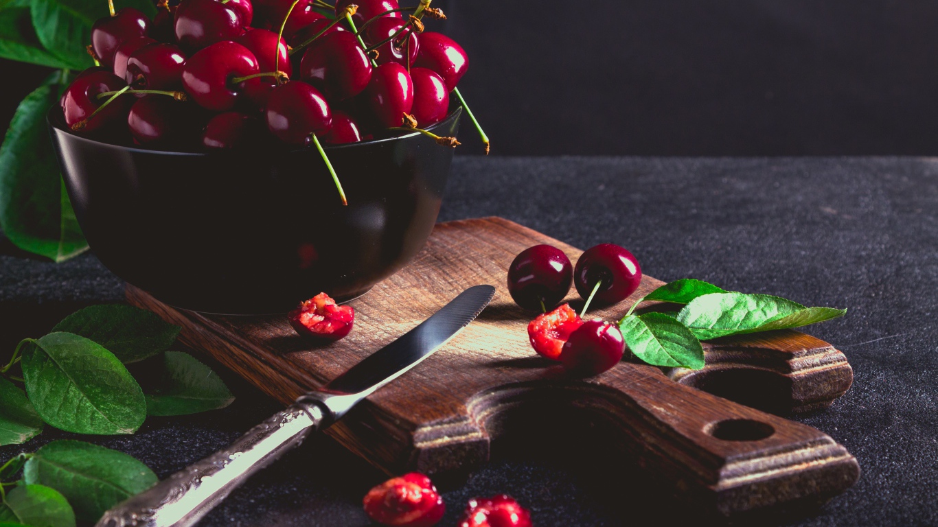 Спелые красные черешни на разделочной доске на столе 