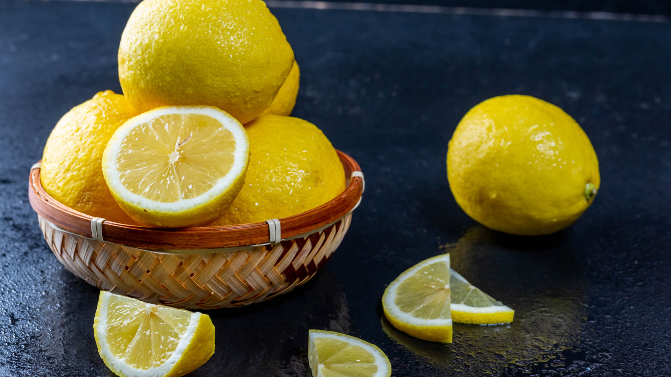 Мокрый лимон с кусочками на черном столе 