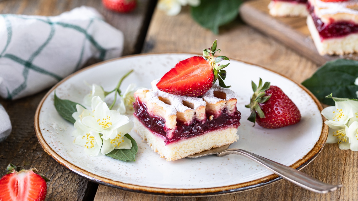Кусок пирога на тарелке с клубникой и цветами жасмина
