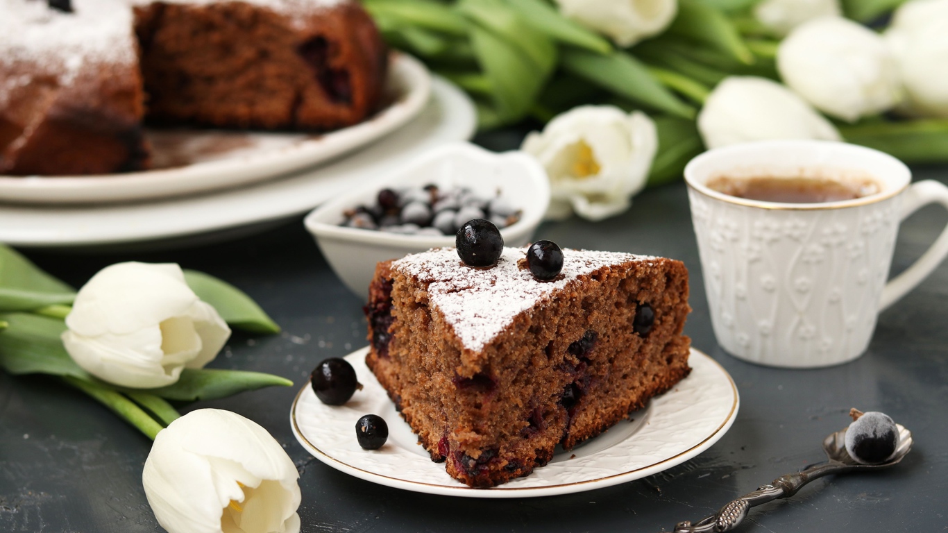 Кусок пирога со смородиной на столе с тюльпанами 