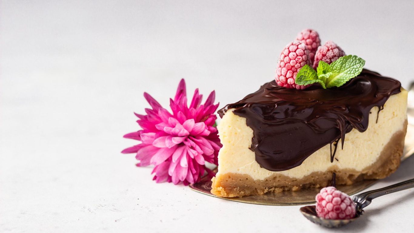Кусок чизкейка с шоколадом на столе с малиной и цветком