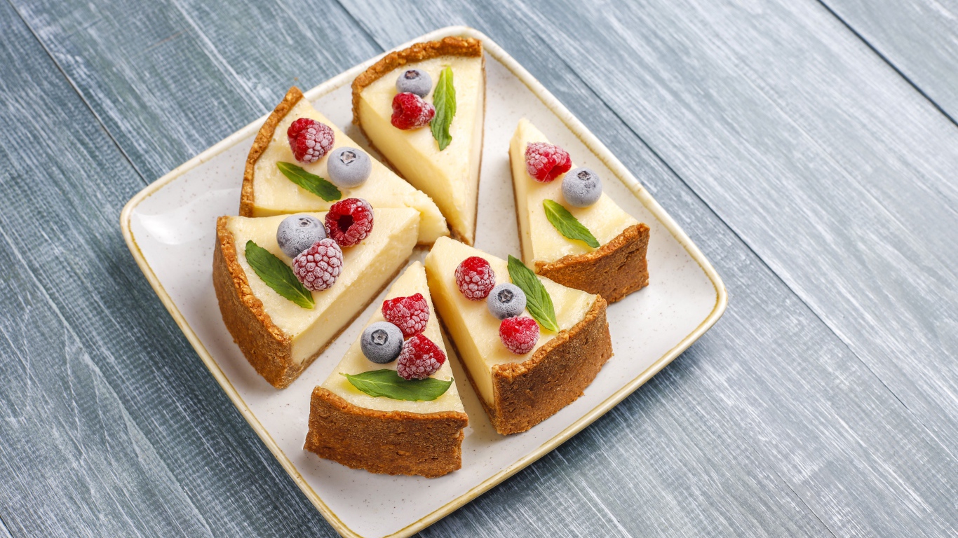 Аппетитный чизкейк с ягодами нарезан кусками на тарелке 