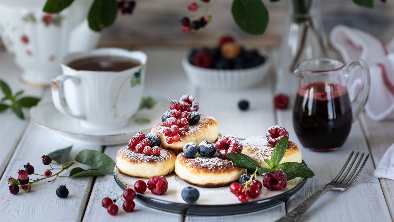 Сырники на столе с ягодами и чаем на завтрак
