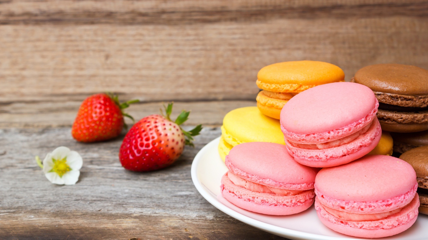 Разноцветный десерт макарун на столе с клубникой