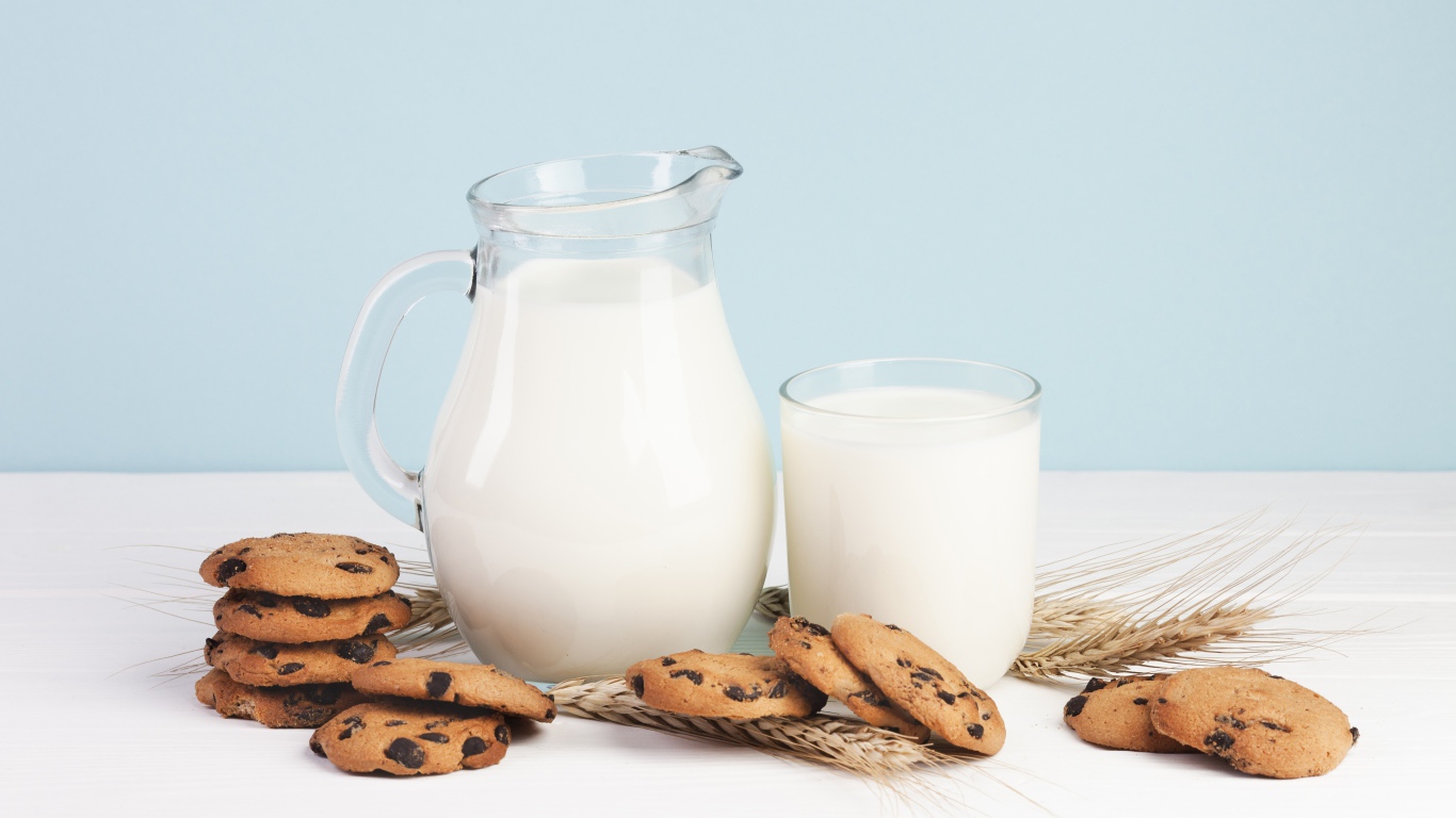 Печенье с шоколадом на столе с молоком и колосьями пшеницы