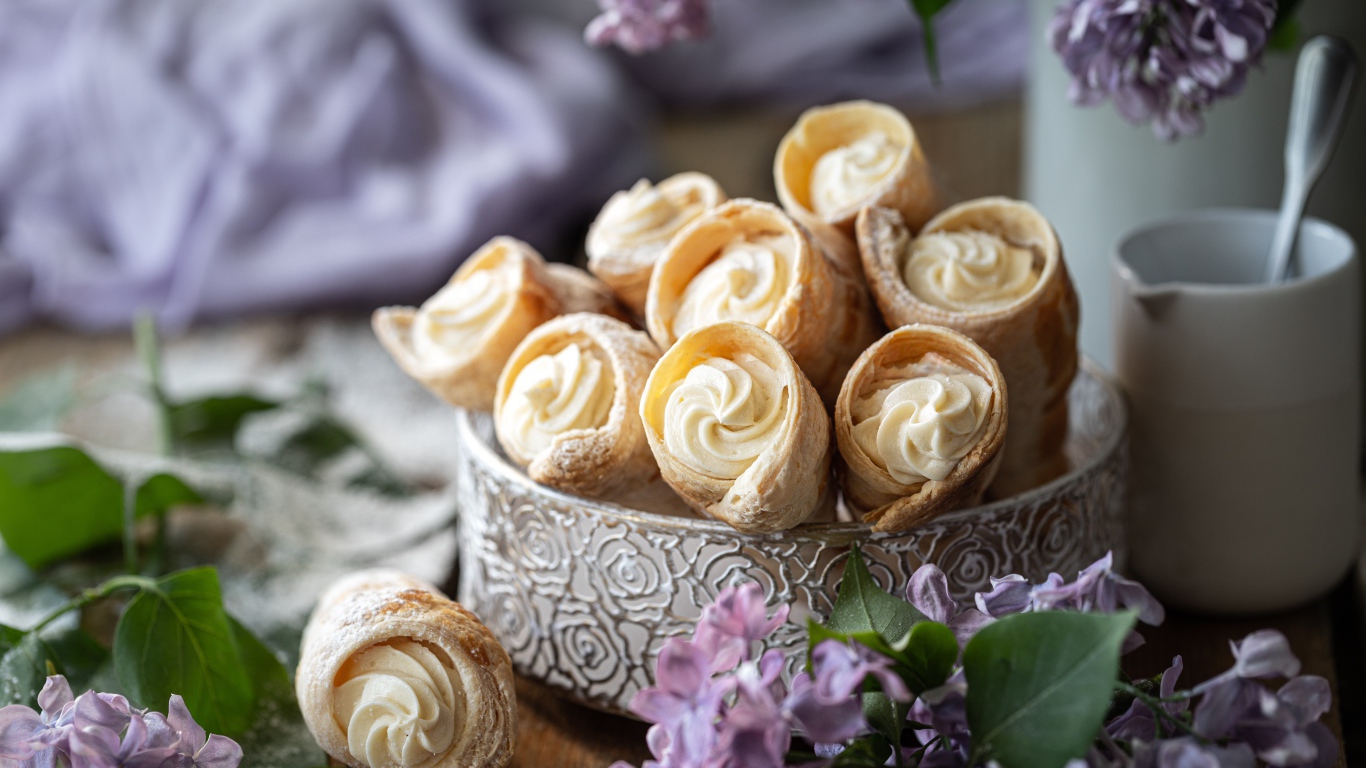 Трубочки с кремом на столе с цветами сирени