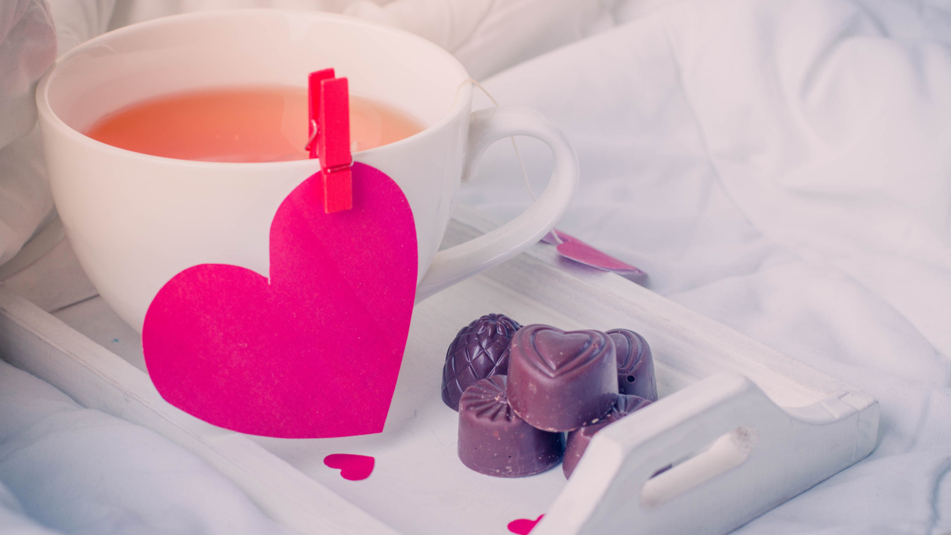 Чашка кофе с красным сердцем и шоколадными конфетами 