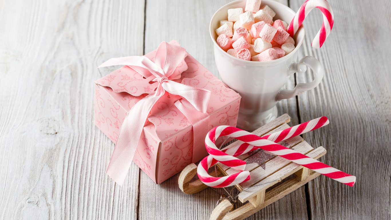 Чашка с маршмеллоу на столе с игрушечными санками и подарком