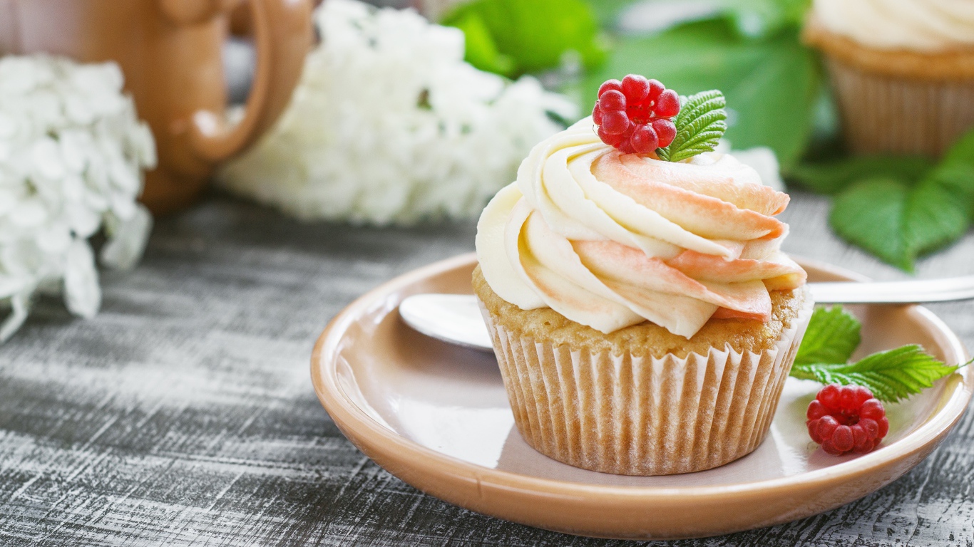 Кекс с кремом и малиной на столе