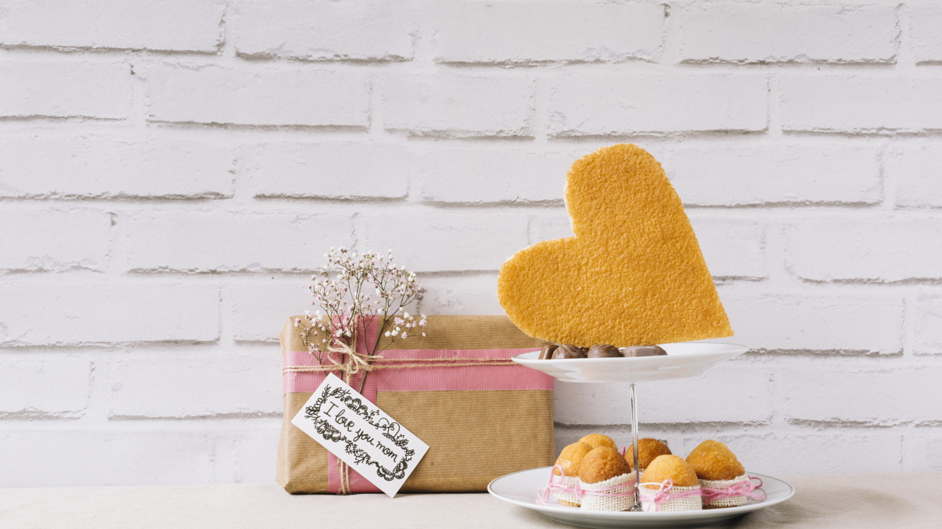 Кексы на тарелке на столе с подарком для любимой 