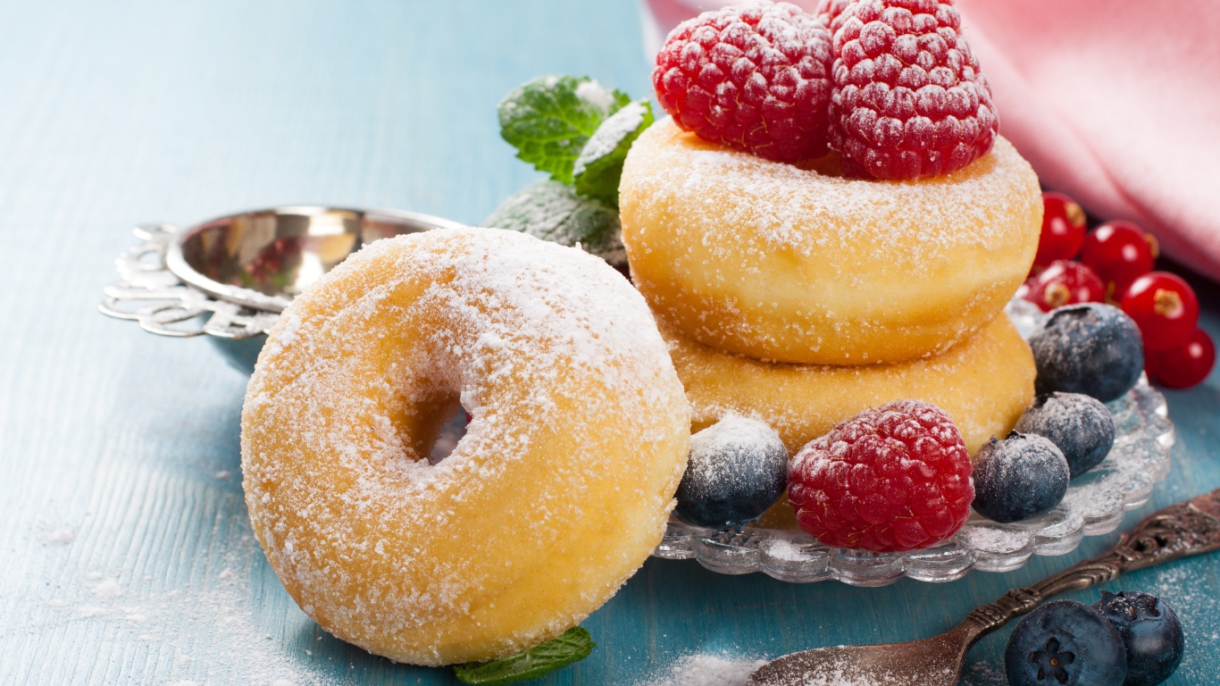 Вкусные пышные пончики с ягодами черники и малины с сахарной пудрой 