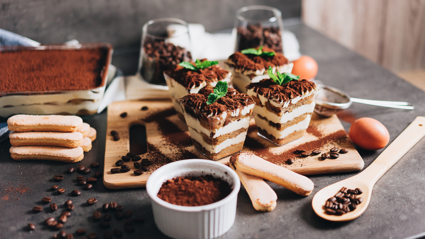 Аппетитный десерт тирамису в креманках на столе с кофейными зернами