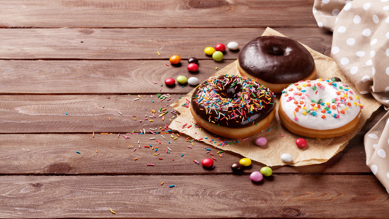 Пончики с глазурью на столе с конфетами на деревянном столе