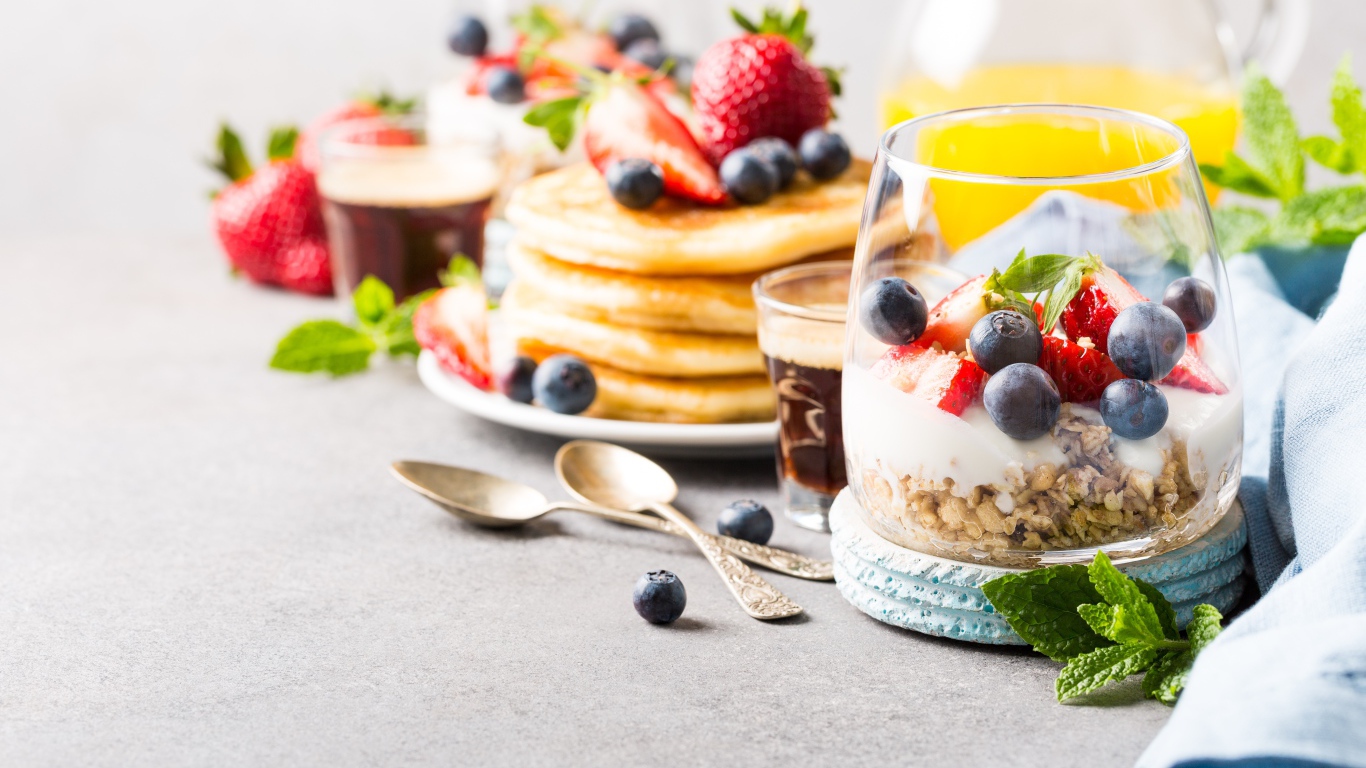 Оладьи на столе с ягодами, мюсли и кофе