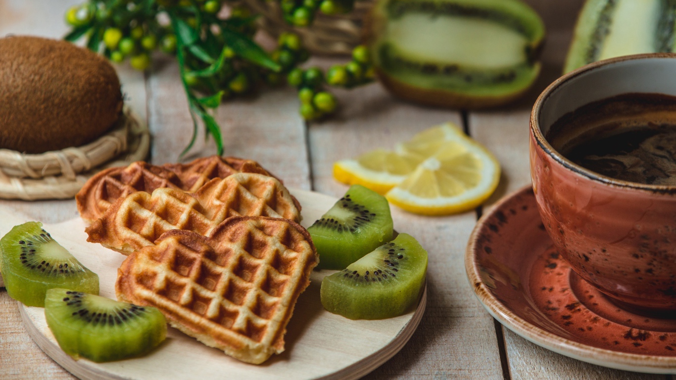 Вафли в форме сердца на доске с киви и чашкой кофе