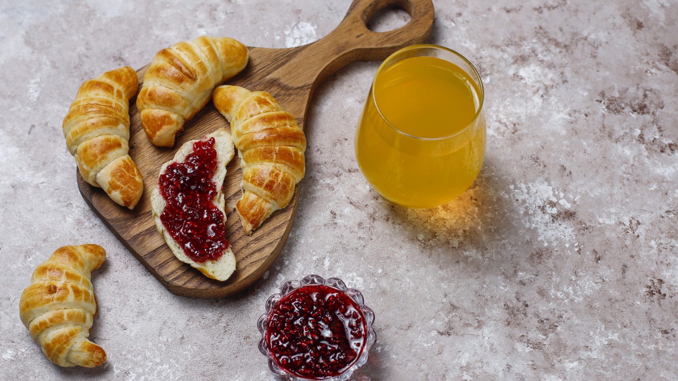 Сок на столе с круассанами и джемом