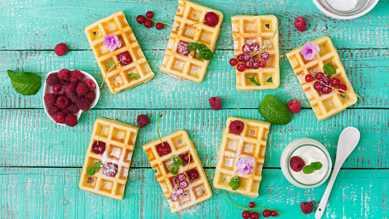 Большие сладкие вафли с ягодами и сахарной пудрой на столе 