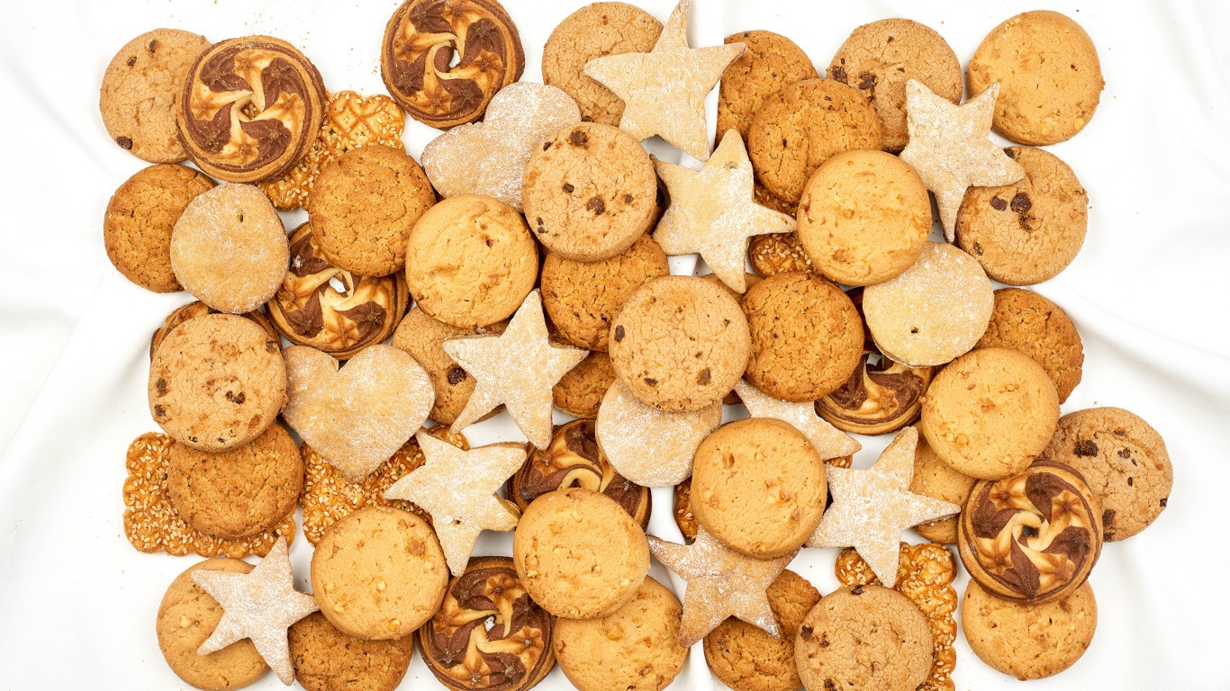 Много песочного печенья разной формы на белом фоне