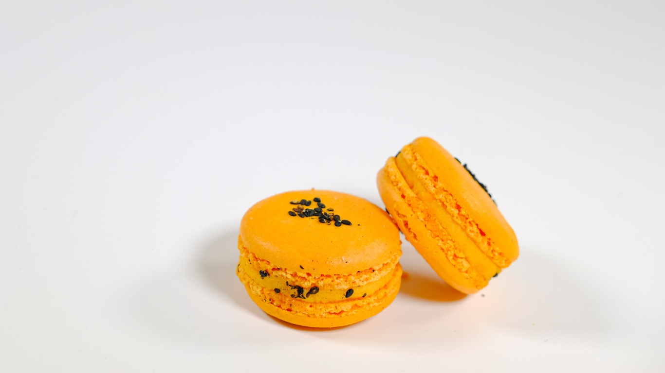 Оранжевый десерт макарон на сером фоне
