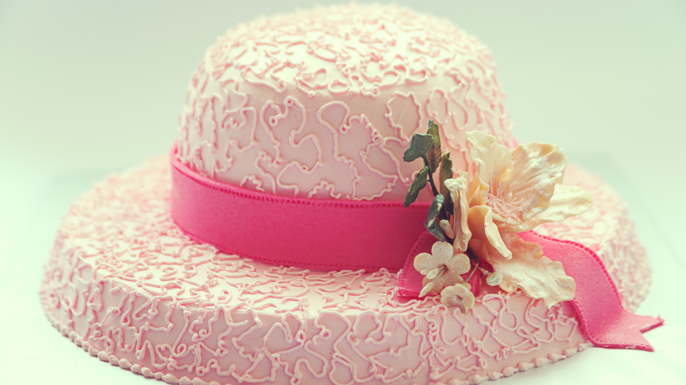 Розовый торт в виде шляпы на столе 