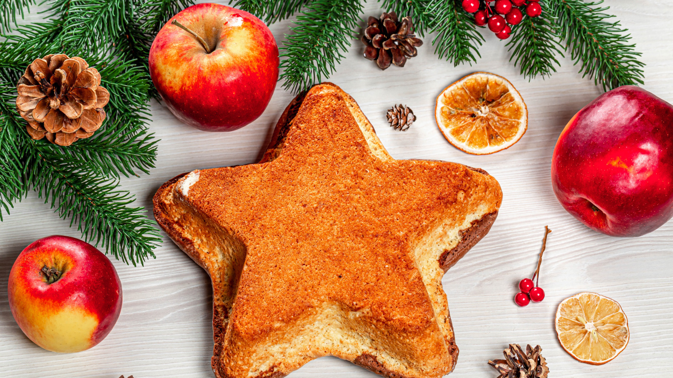 Пирог в форме звезды на столе с яблоками и еловыми ветками 