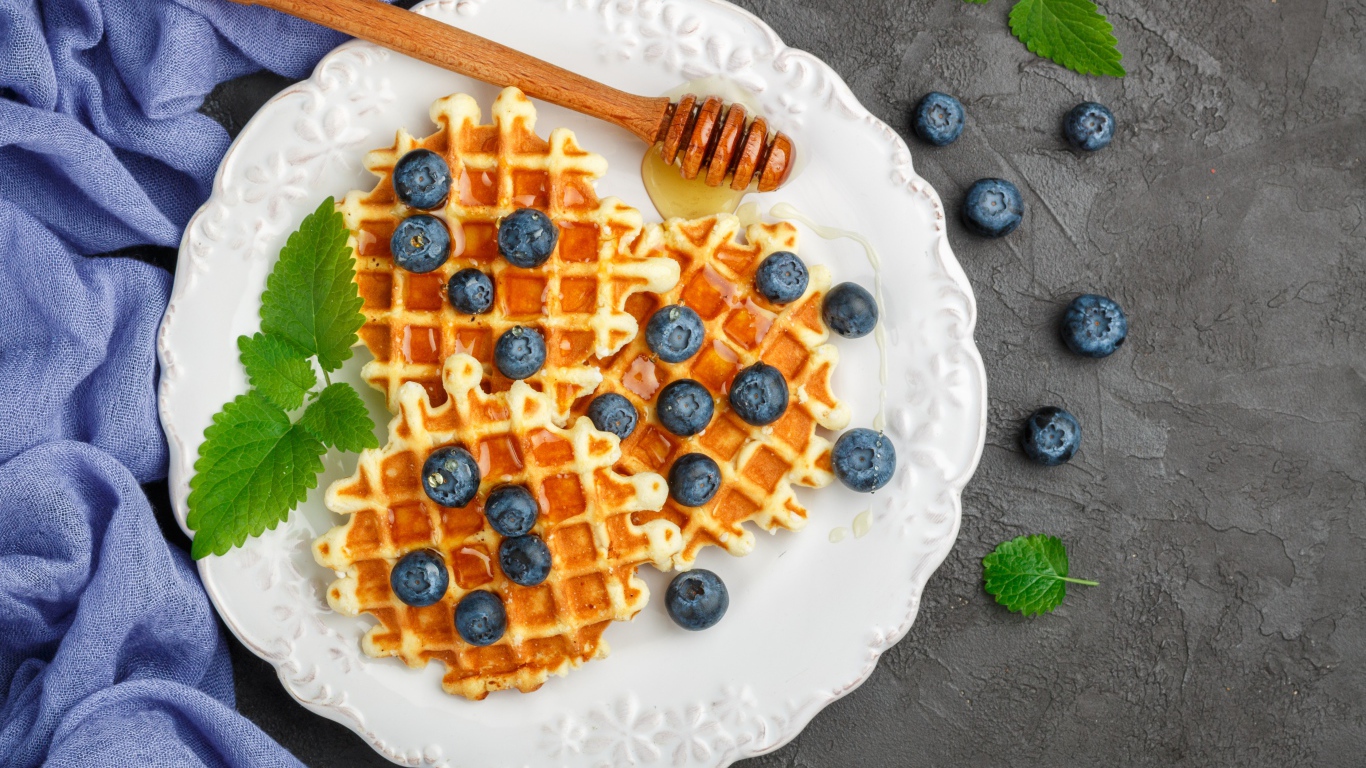 Сладкие вафли с медом на тарелке с ягодами черники
