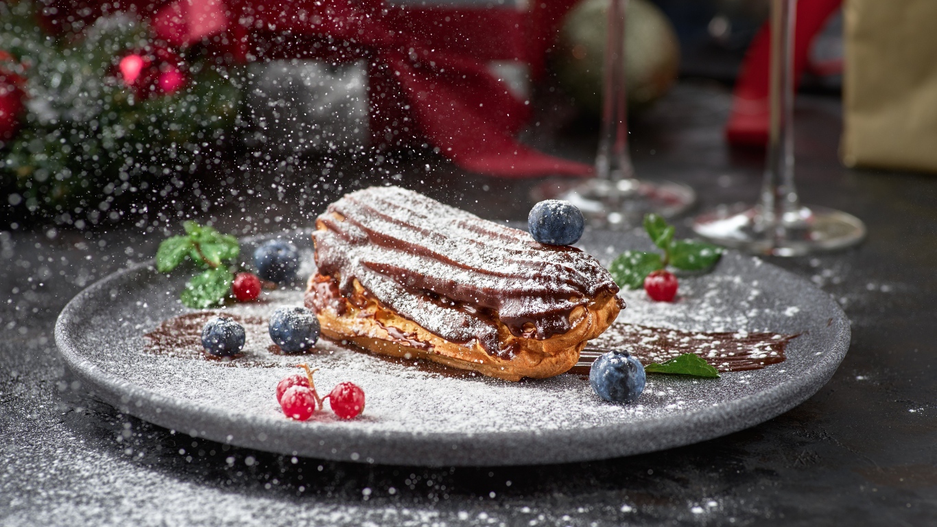 Вкусное пирожное на тарелке с сахарной пудрой и ягодами