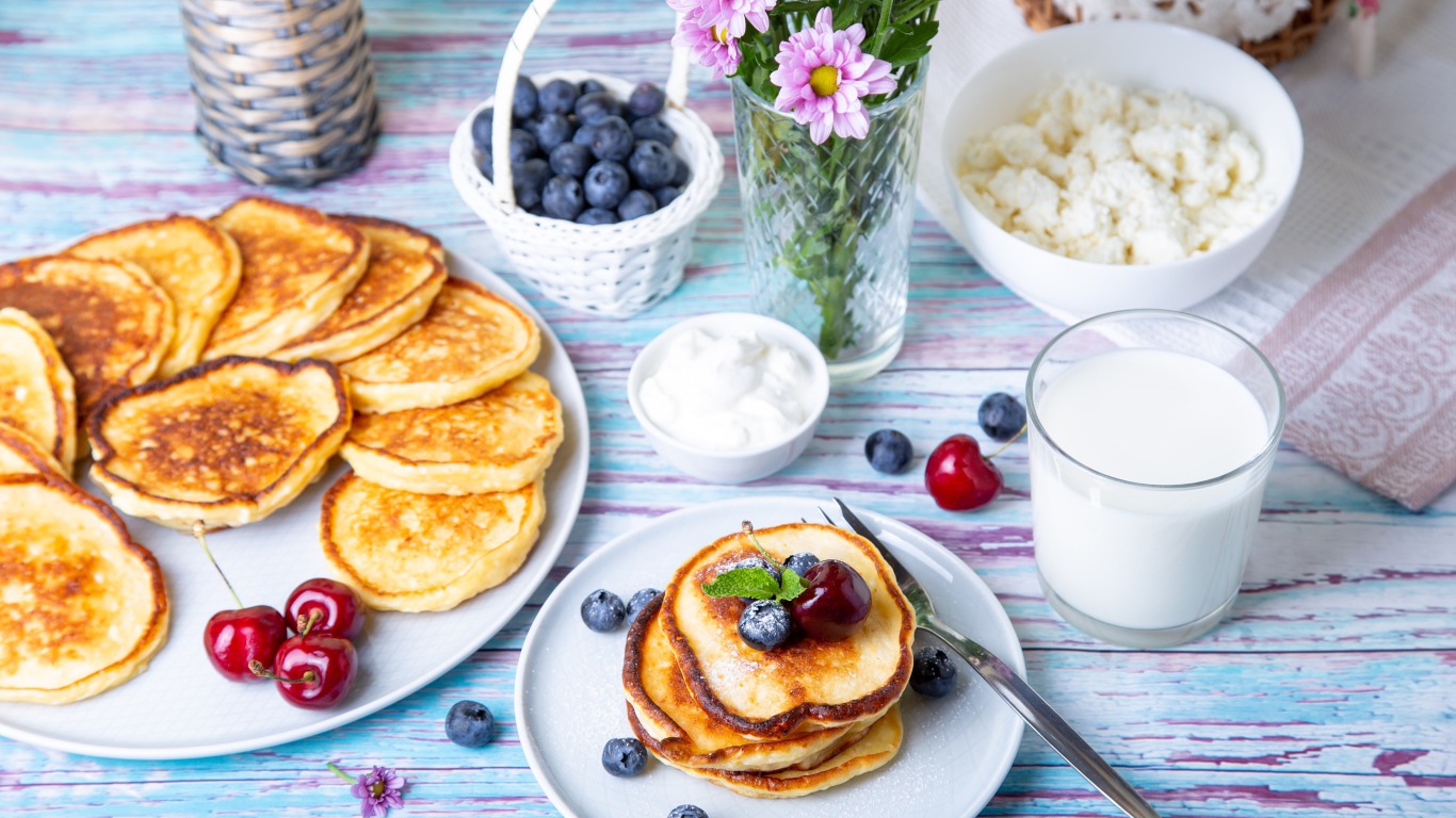 Вкусные оладьи на столе с ягодами черники, творогом и молоком