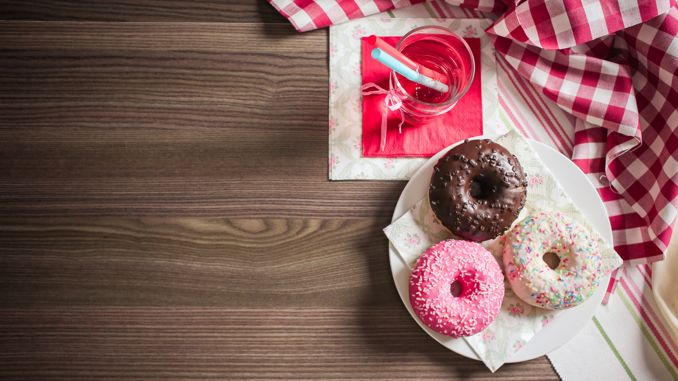 Три сладких пончика с глазурью на столе с лимонадом