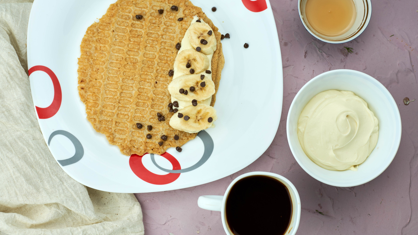 Вафля с бананами на столе с кофе и сметаной 