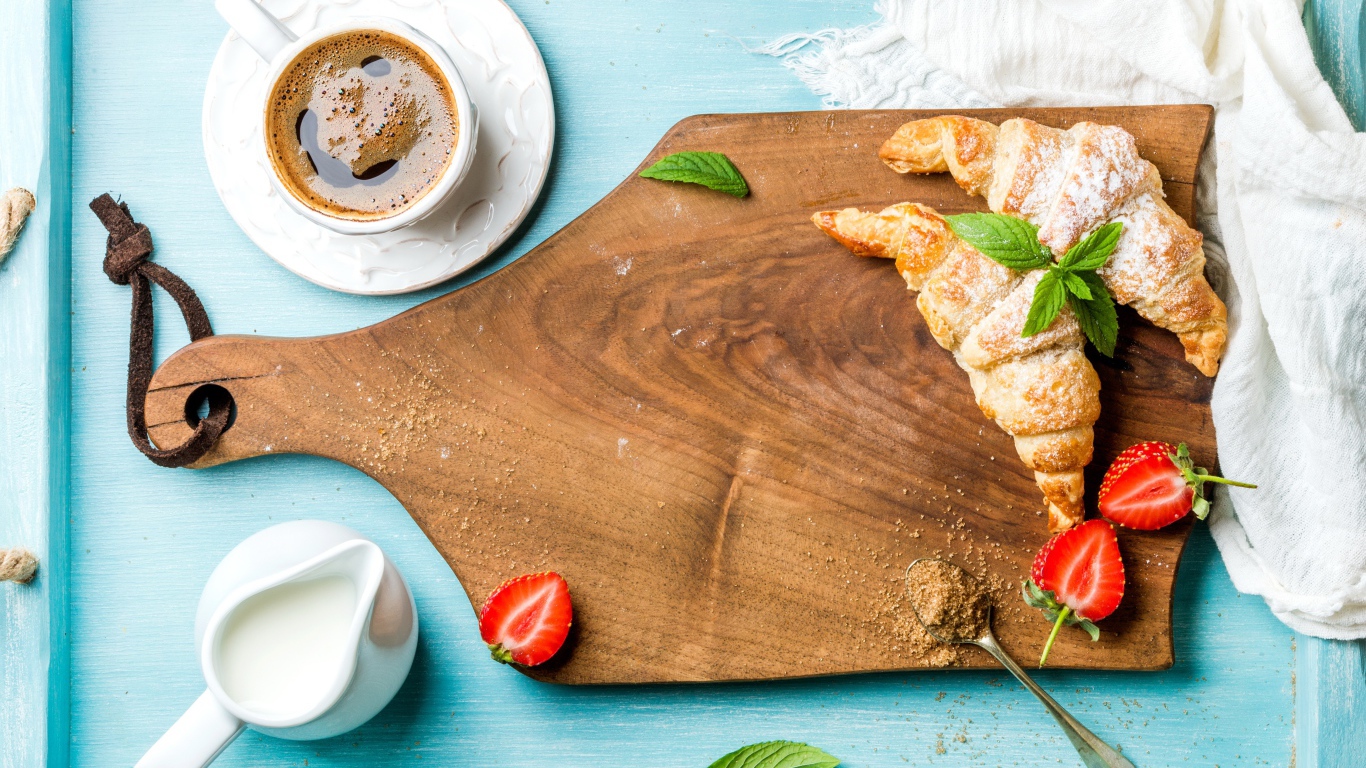 Деревянная доска на столе с круассанами и чашкой кофе