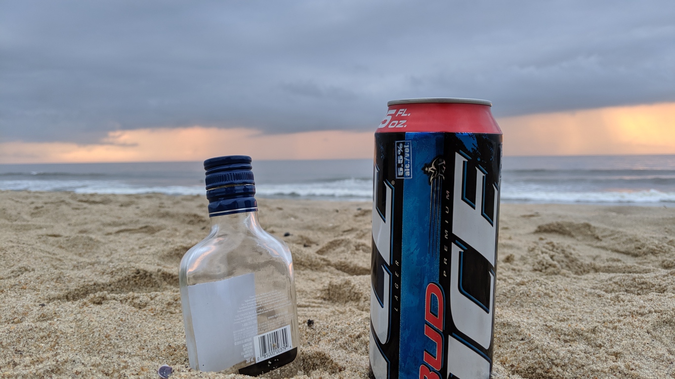 Бутылка пива и бутылка водки на песке у моря