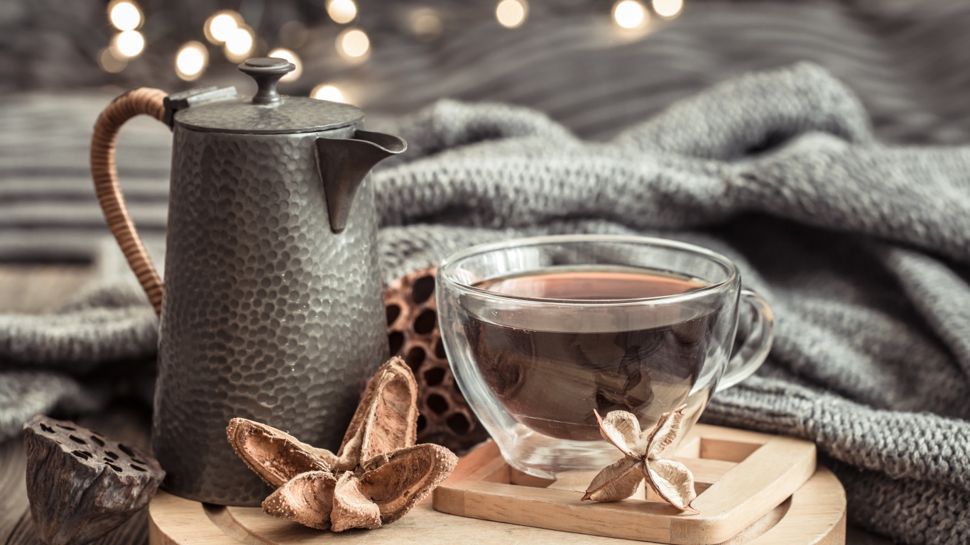 Чашка чая на столе с чайником и теплым пледом