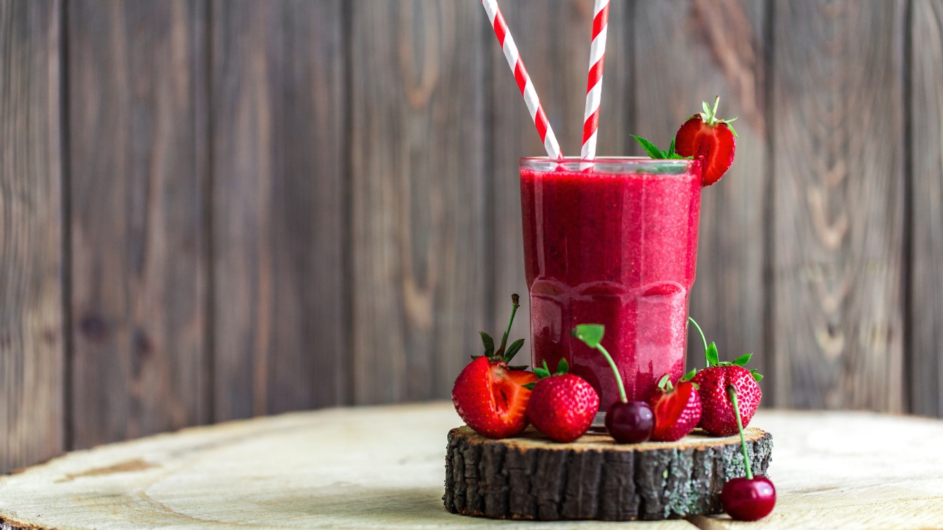 Стакан ягодного смузи на столе с клубникой и вишней