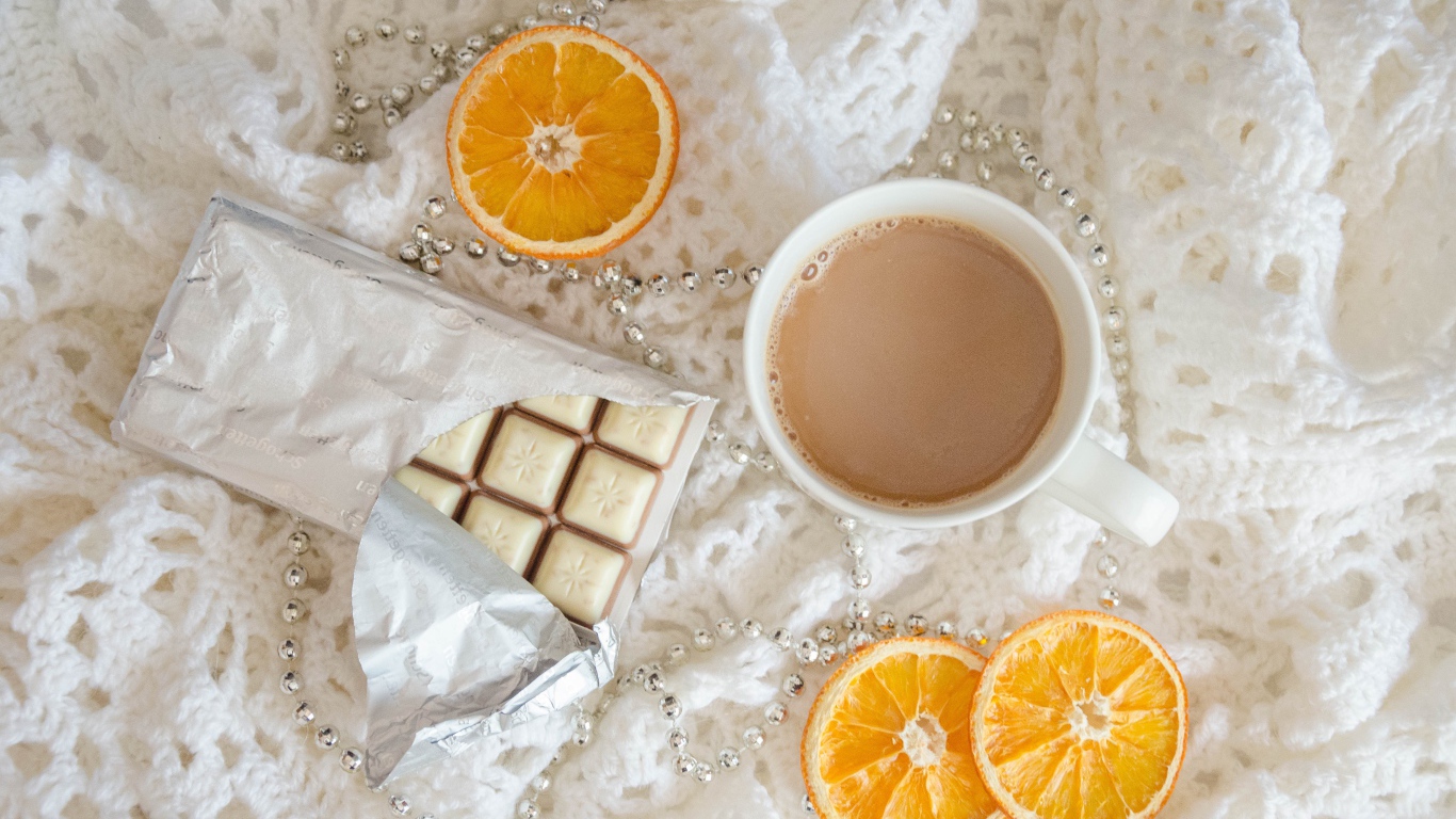 Чашка какао, шоколад и апельсин на белом пледе