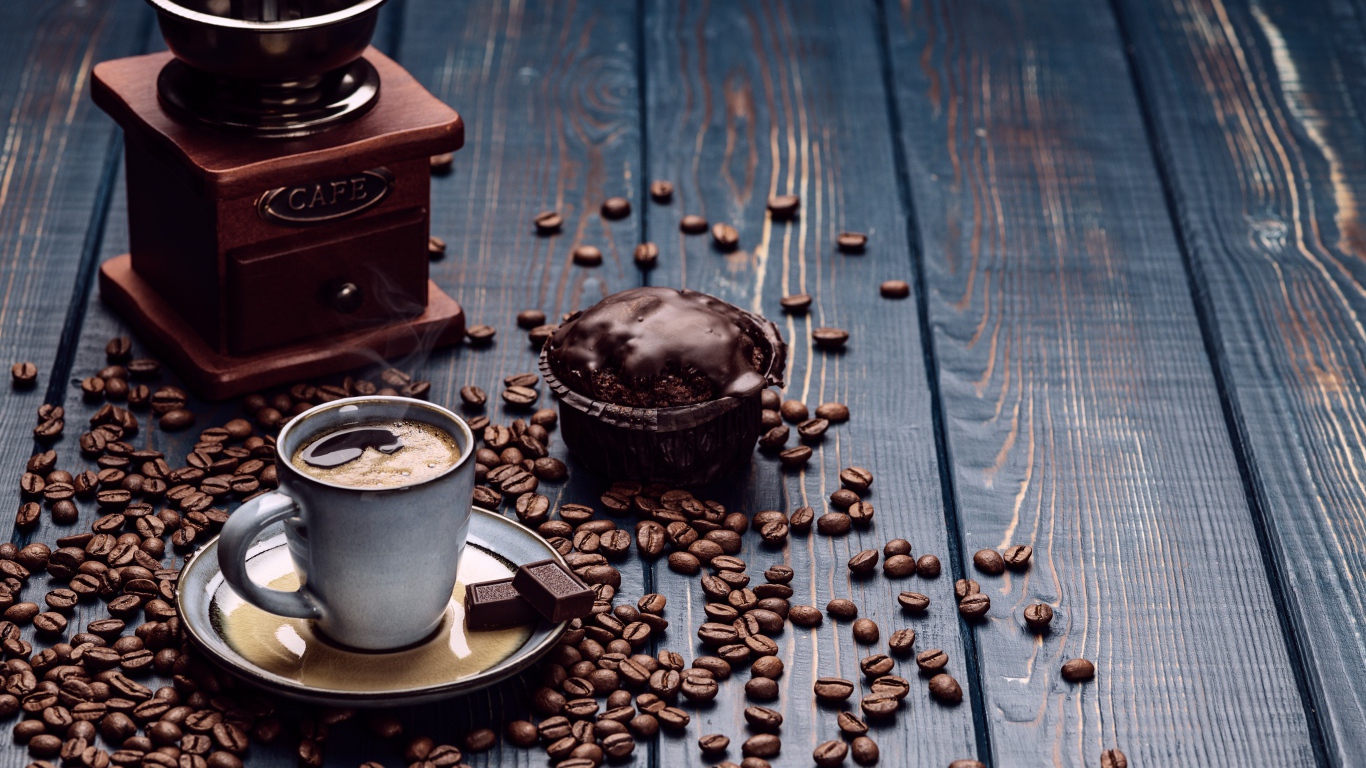 Чашка кофе на столе с шоколадным кексом и кофемолкой