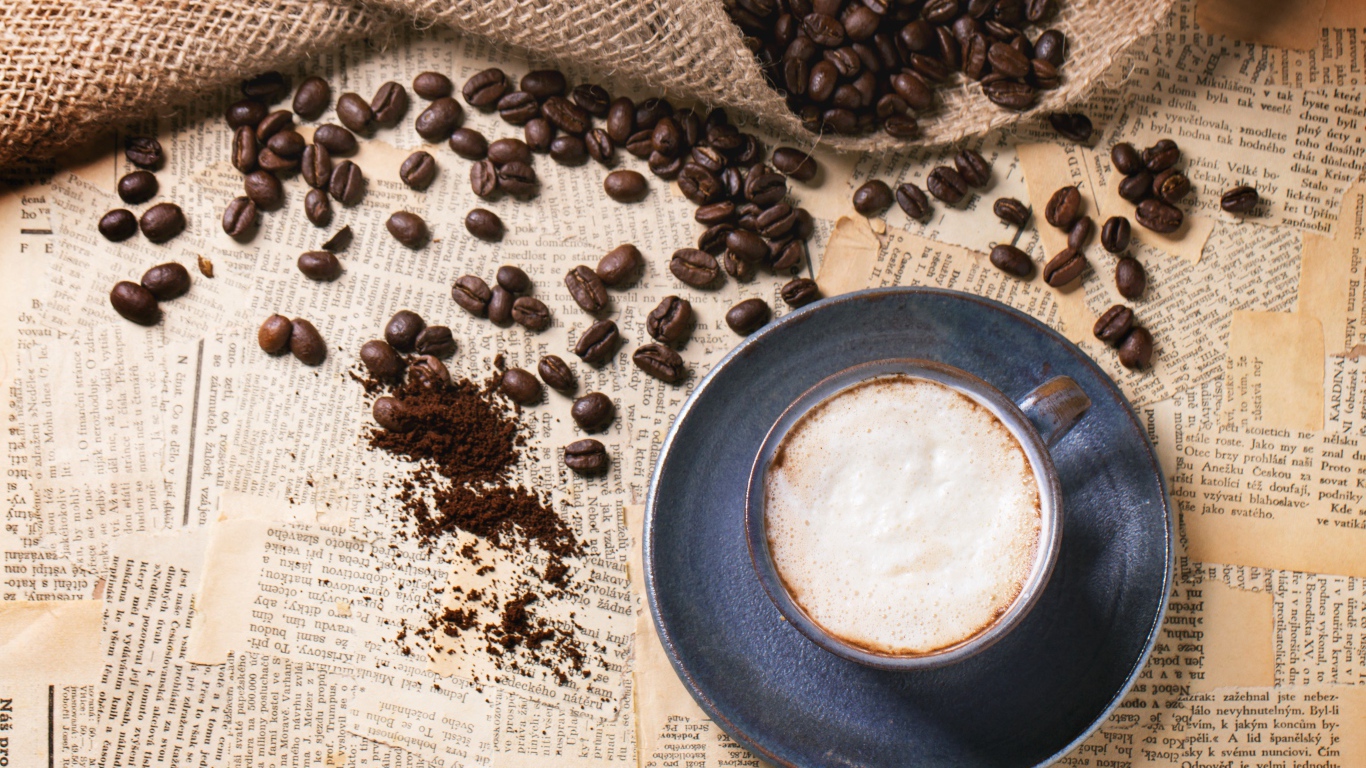 Чашка кофе на столе со старыми газетами и зернами