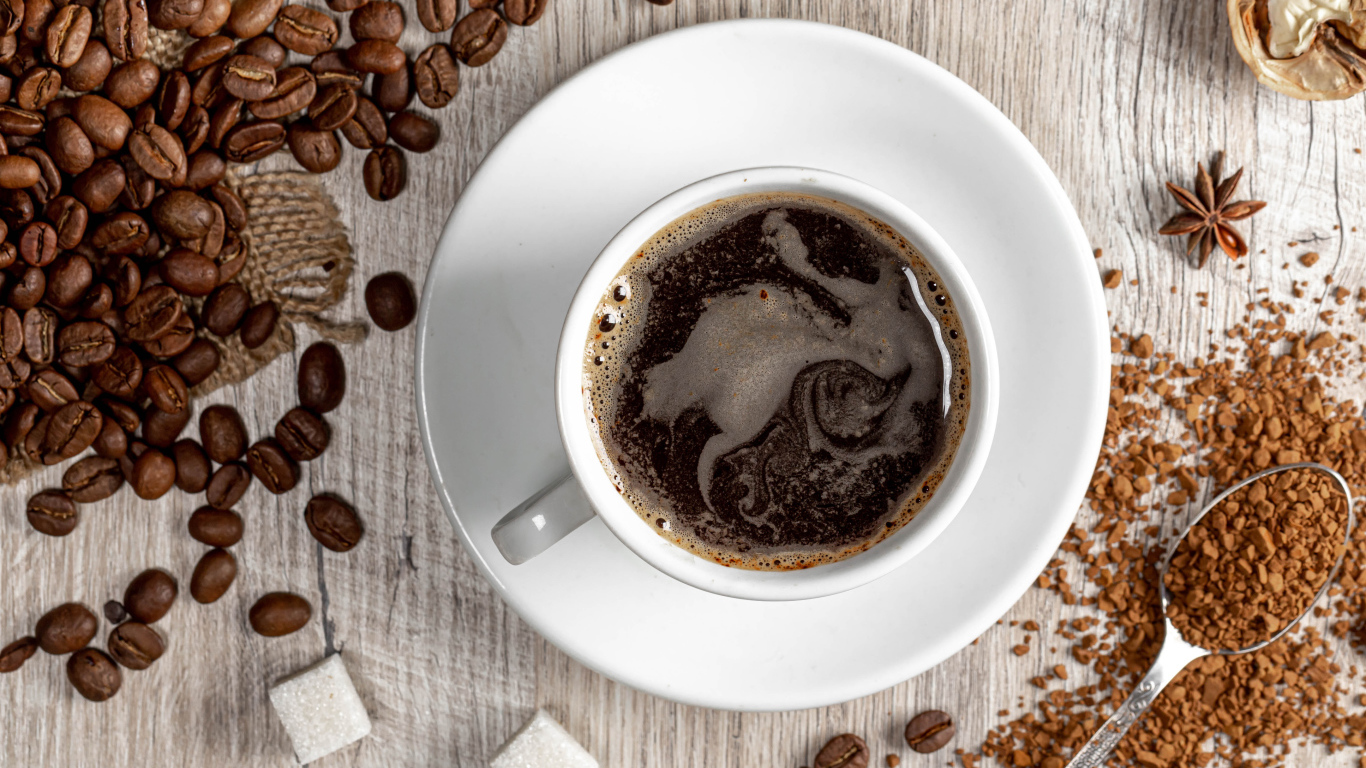 Чашка кофе на столе с сахаром и кофейными зернами