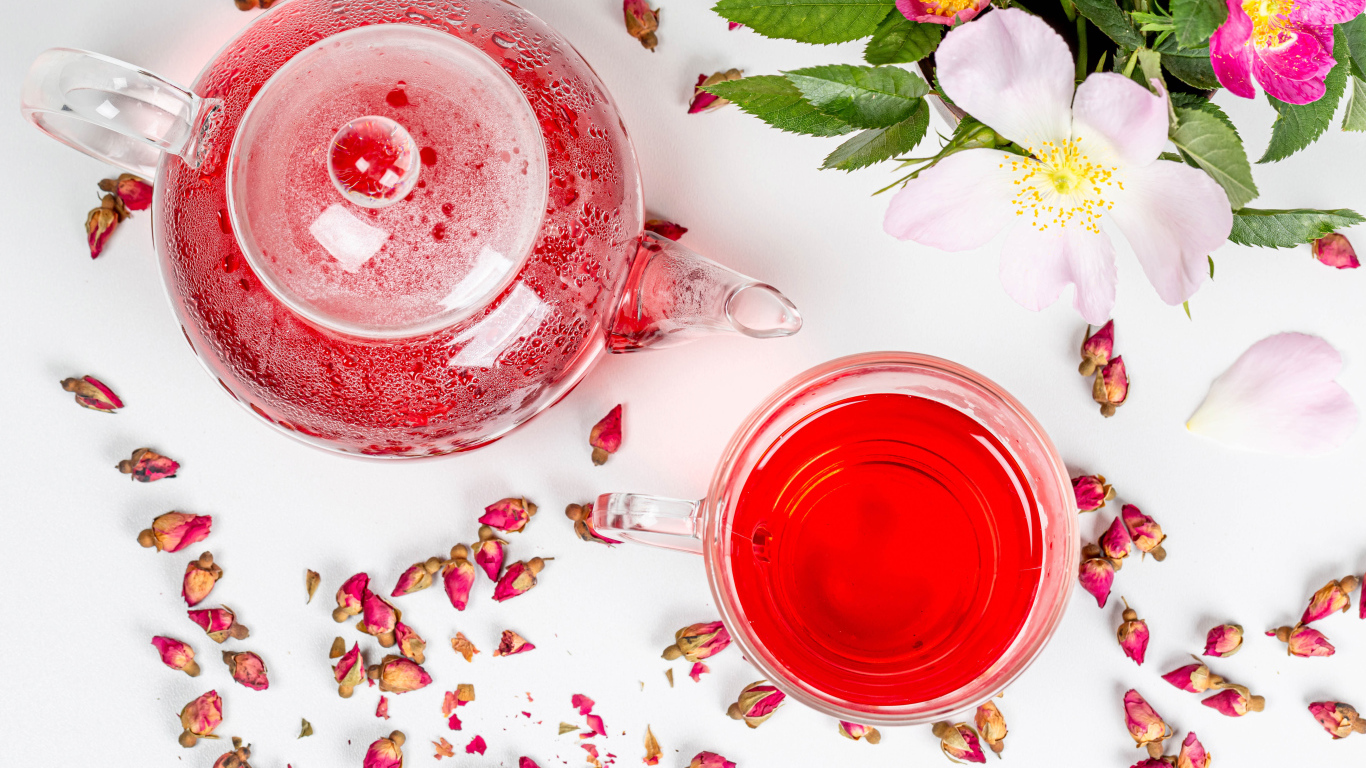 Свежий чай с шиповника в стеклянной чашке на столе с чайником