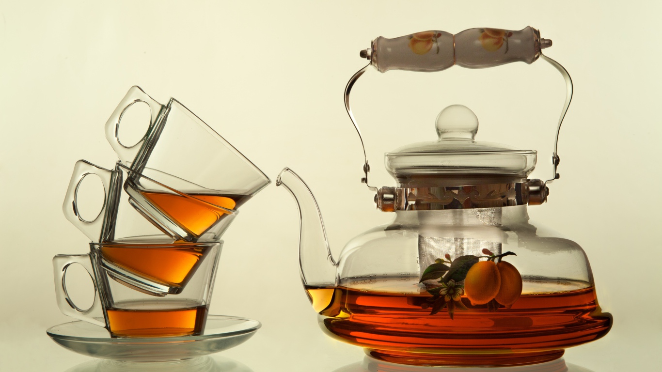 Стеклянный чайник с чашками на белом фоне