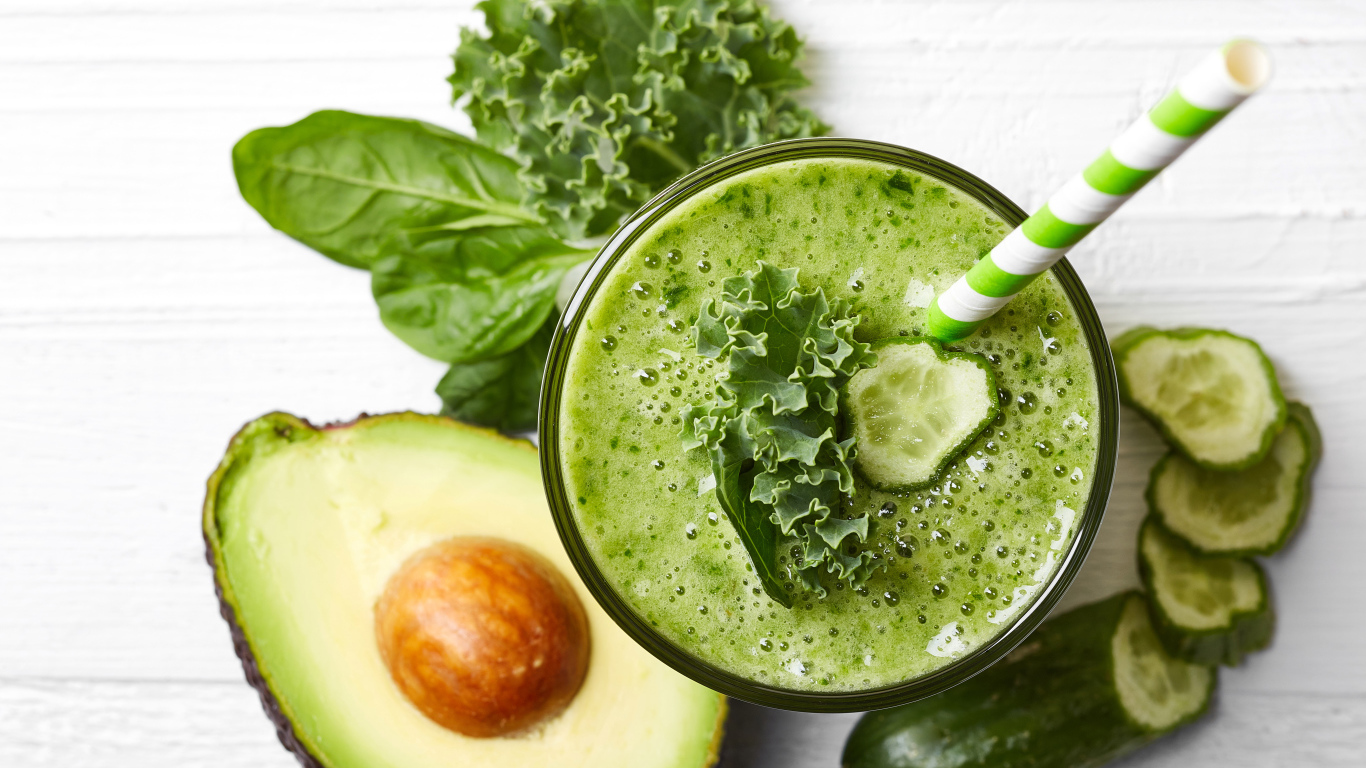 Зеленый смузи на столе с огурцом, авокадо и зеленью