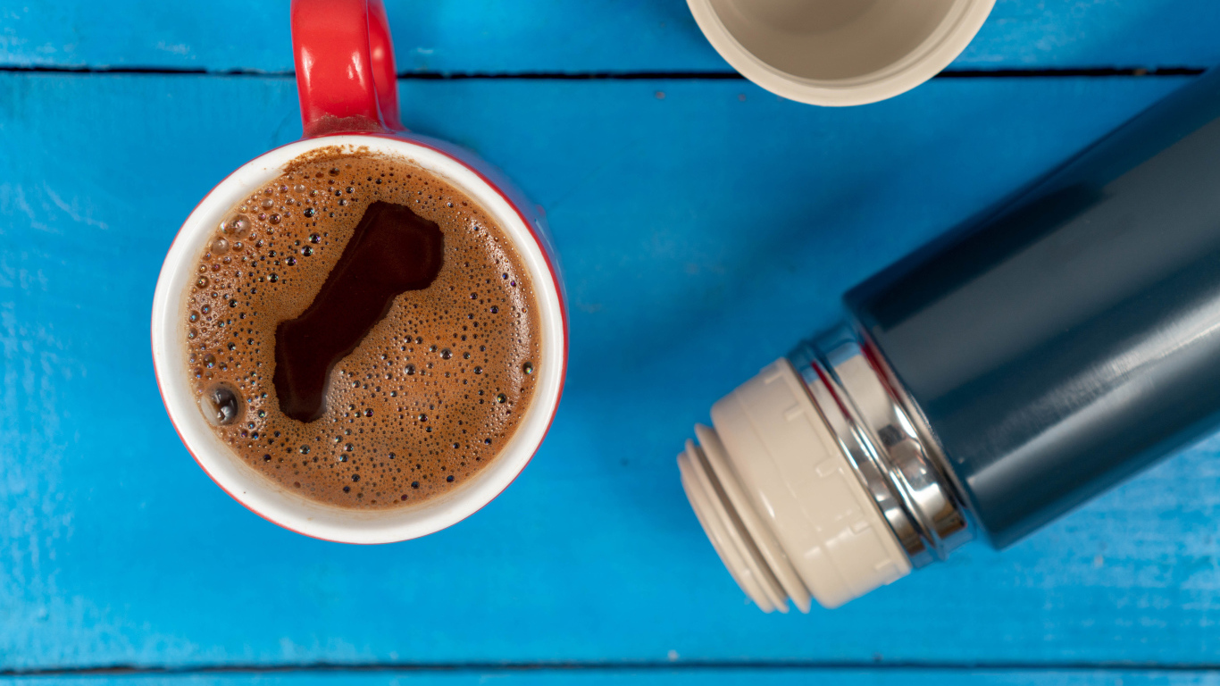 Красная чашка кофе с термосом на голубом столе 