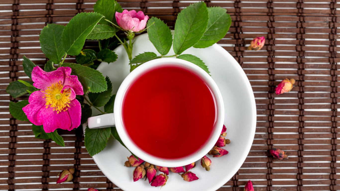 Красный чай с шиповника на столе с цветами