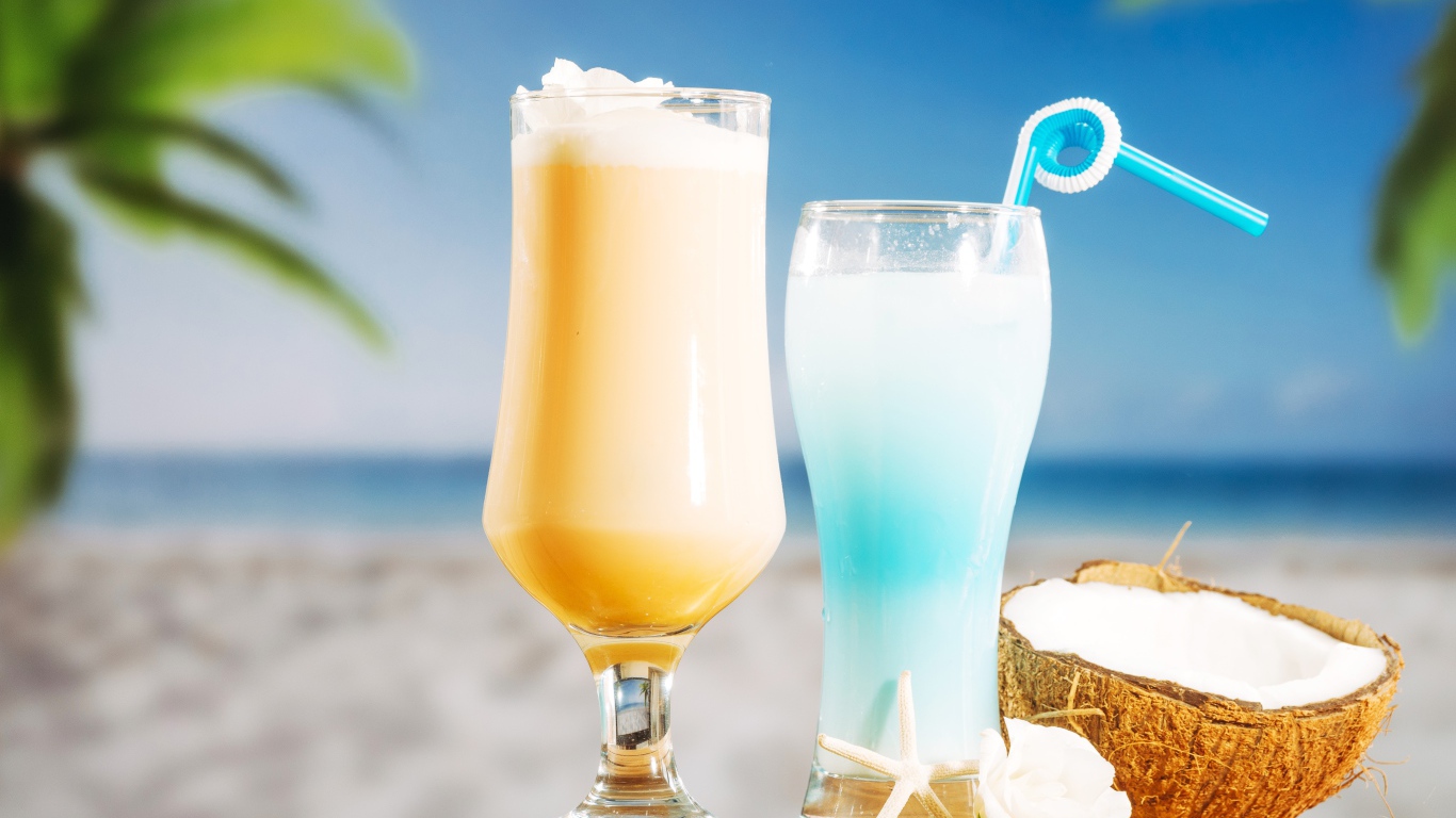 Два коктейля с кокосом на столе на тропическом пляже