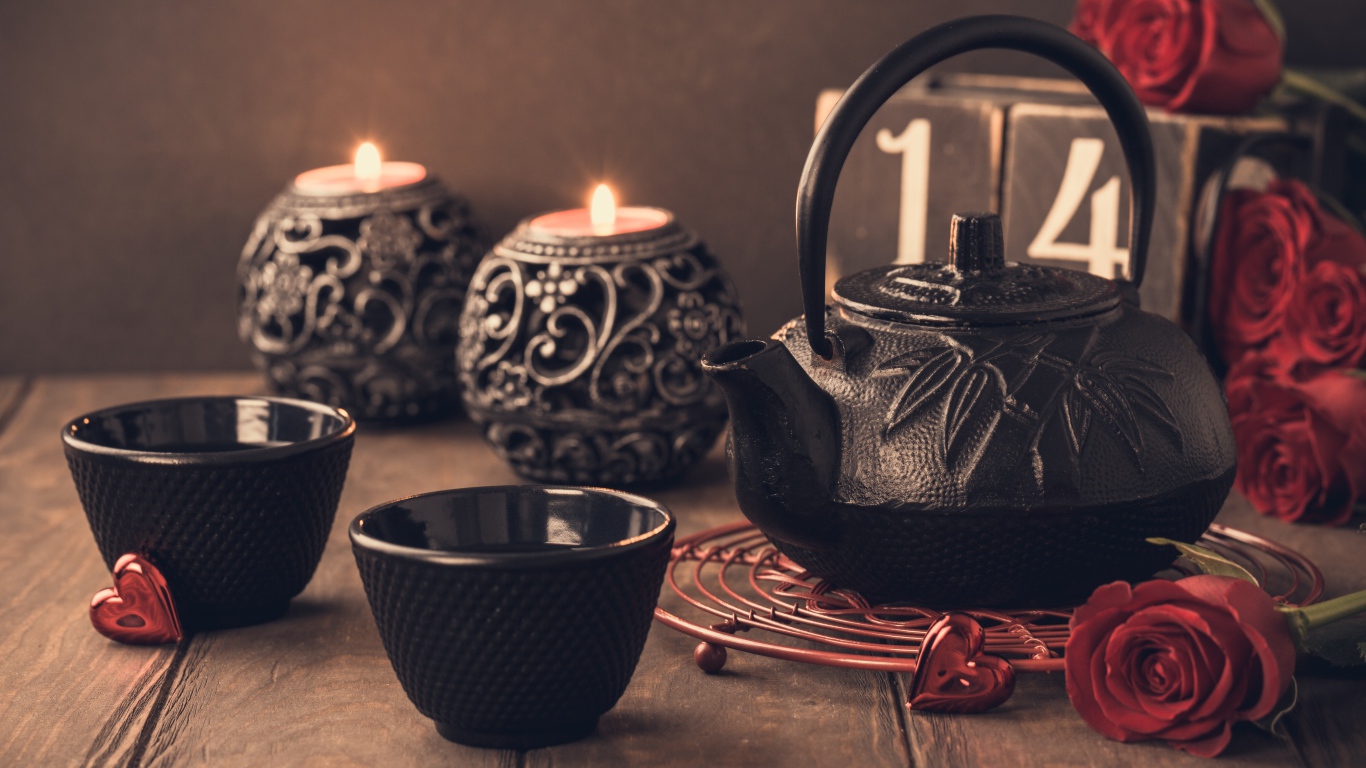 Две чашки чая на столе со свечами и красными розами