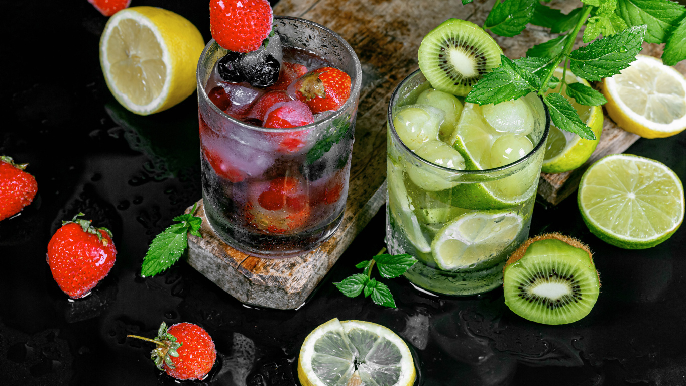 Два стакана мохито на столе с мятой, лимоном и клубникой 