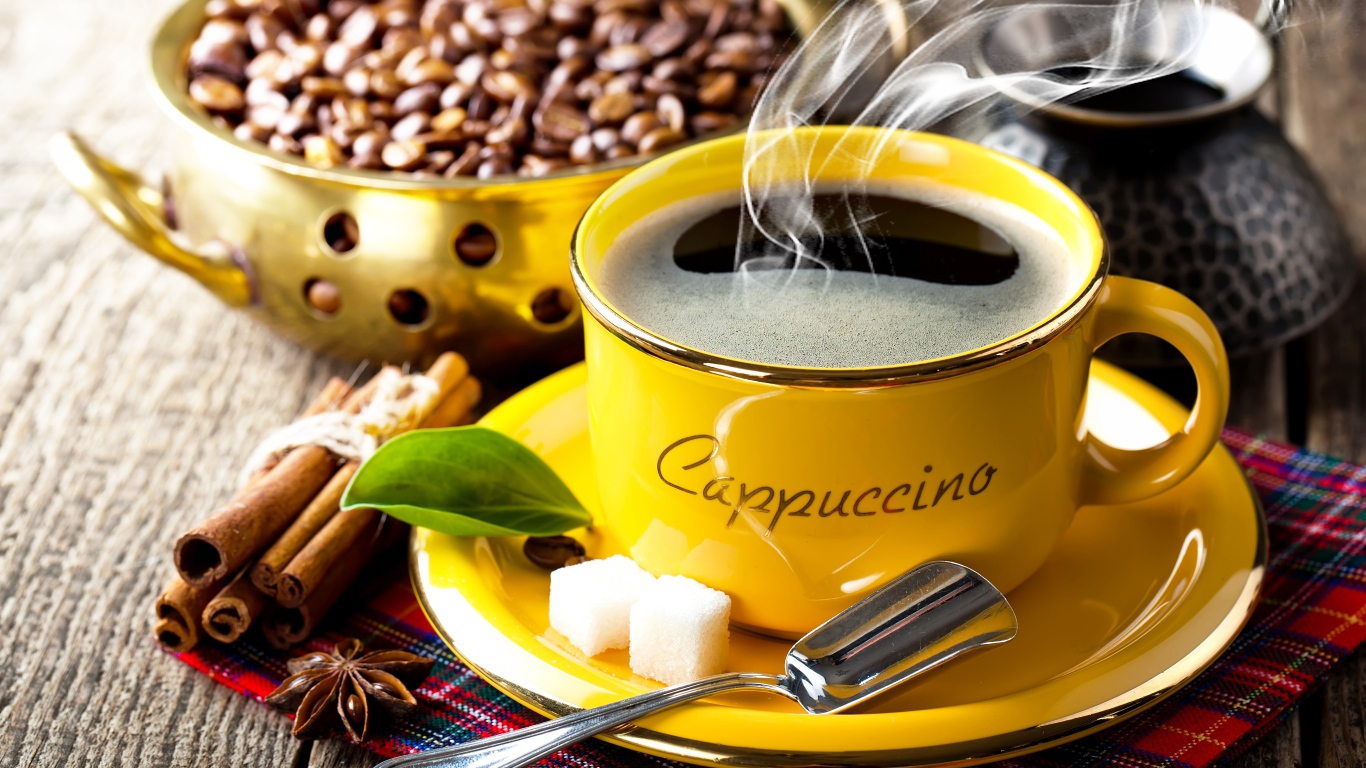 Желтая чашка с горячим кофе на столе с зернами и корицей 