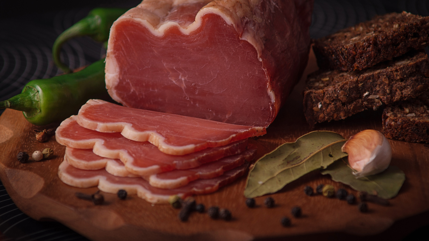 Кусок вяленого мяса на доске с черным хлебом и специями