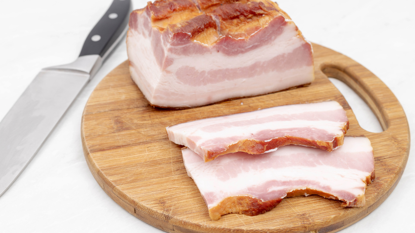 Кусок вкусного копченого сала на доске с ножом
